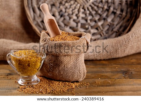 Mustard seeds in bag and sauce in sauce-boat on  wooden background