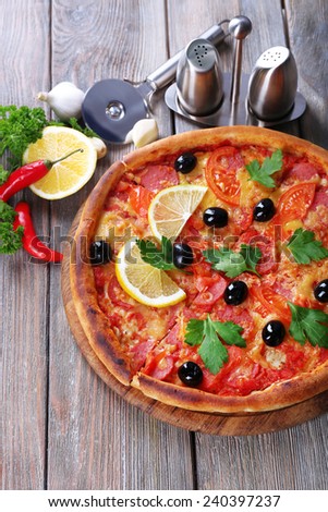 Tasty pizza with spices and round knife on board and wooden table background
