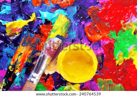 Cans of paint and brush on colorful painted background