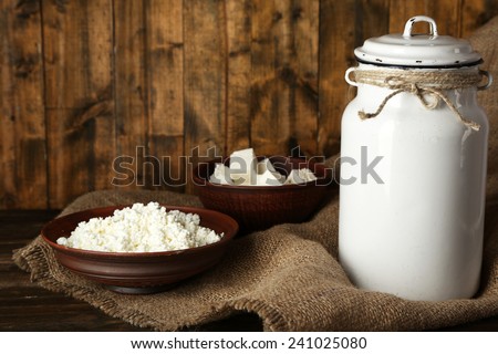 Milk can with cottage cheese on rustic wooden background