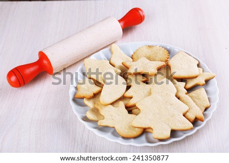 Gingerbread cookies on plate with copper cookie cutter and rolling pin on wooden table background