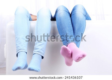 Male and female legs on sofa close-up