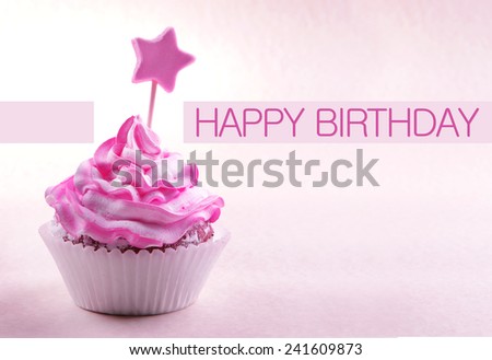 Delicious cupcake with star on stick and Happy Birthday text on light pink background