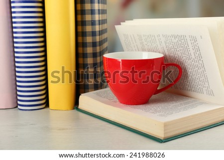 Color cup of tea with books on table, on light blurred background