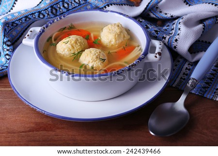 Soup with meatballs and noodles in bowl, on napkin, on wooden background
