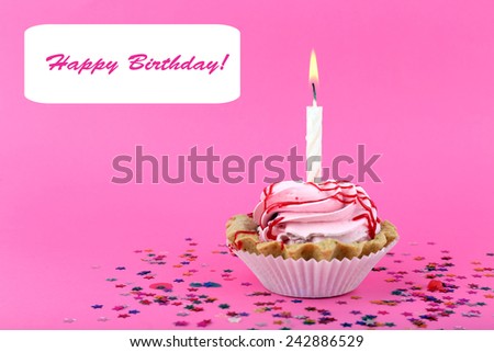 Birthday cup cake with candle and colorful stars on pink background