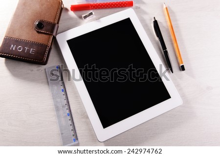 Tablet PC with notebook on wooden table background