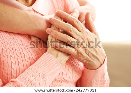 Old and young hands hug, closeup