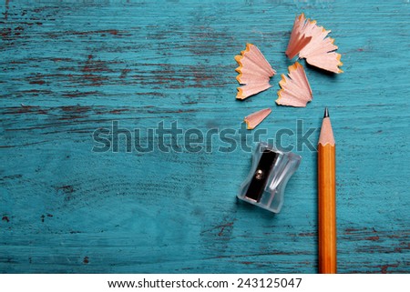Pencil with sharpening shavings on color wooden background