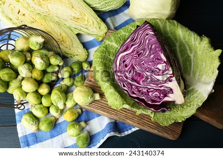 Still life with assortment cabbages on cutting board on color wooden background