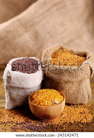 Mustard seeds in bags and sauce in bowl on  wooden background
