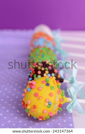 Sweet cake pops on table on purple background