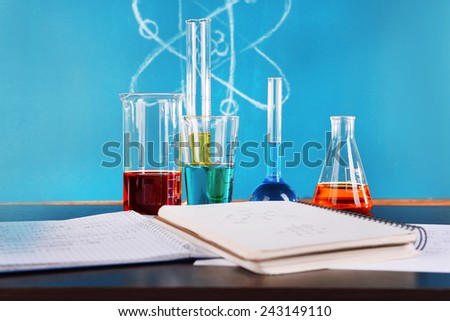 Glassware with chemical agent on desk, on green blackboard background