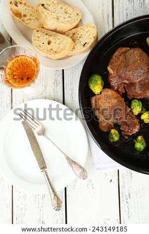 Roasted meat and vegetables on pan, on wooden table background
