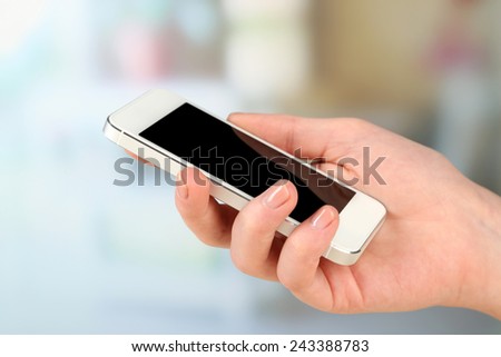 Hand using smart mobile phone on light blurred background
