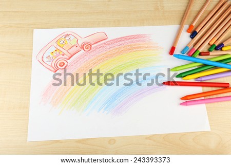 Drawing made by child with colorful pencils on wooden table background
