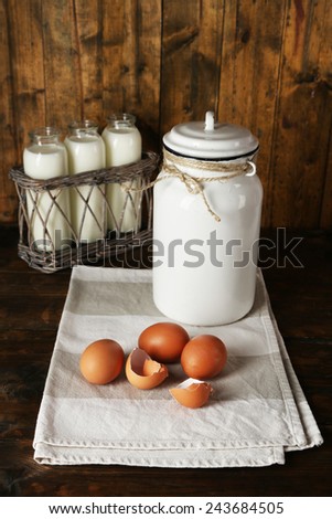 Milk can with eggs, eggshell and  glass bottles on rustic wooden background