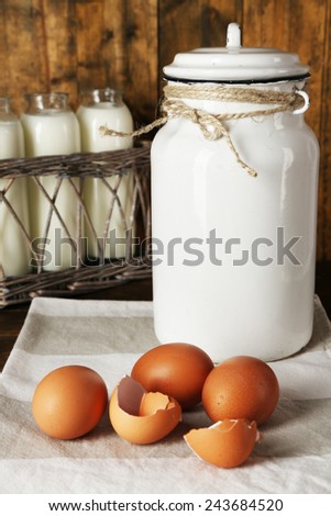 Milk can with eggs, eggshell and  glass bottles on rustic wooden background