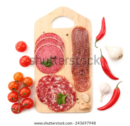 Various sliced salami with cherry tomatoes, chili pepper and spices on wooden cutting board isolated on white