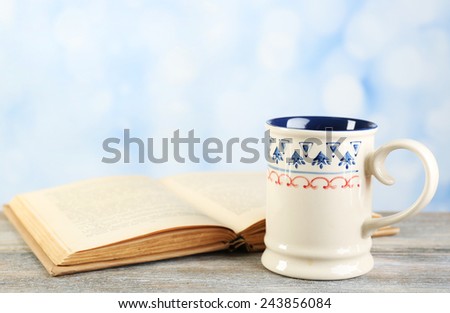 Cup of tea and book on table, on bright background