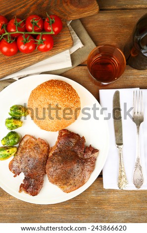 Roasted meat and vegetables on plate, on wooden table background