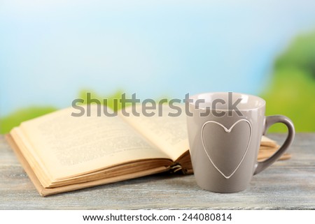 Cup and book on table, on bright background