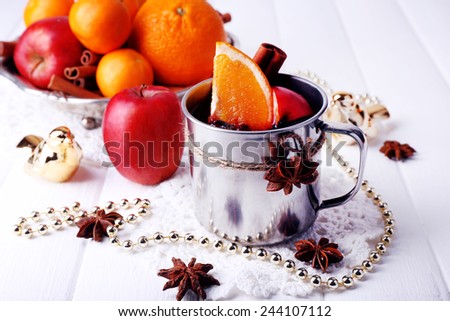 Metal mug of mulled wine fruits, spice and Christmas decoration on color wooden background