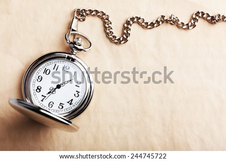 Silver pocket clock on old paper background