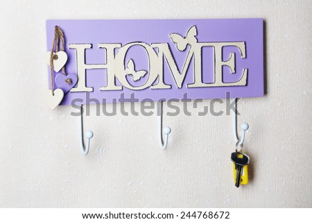 Key hanging from hook, on light wall background