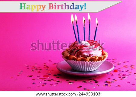 Birthday cup cake with candles and colorful stars on pink background