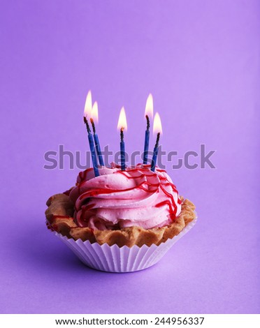 Cake with birthday candles on purple background