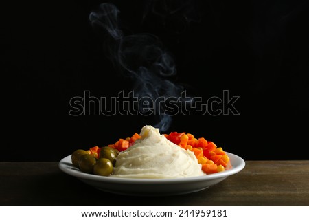 Delicious home cooked food with steam on table on black background