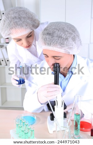 Male and female scientists with microscope in laboratory
