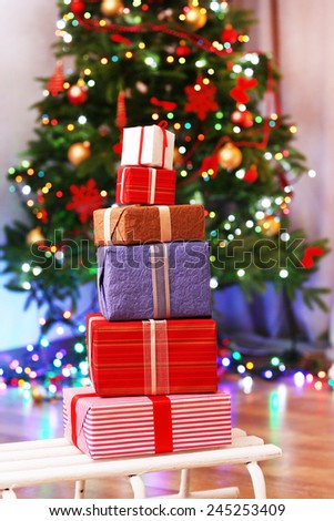 Present boxes on sledge on wooden floor near Christmas tree, indoors