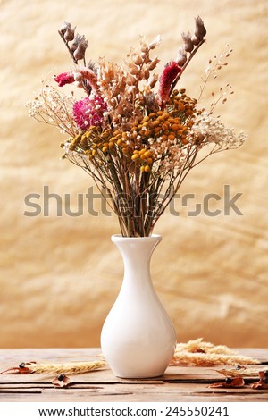 Bouquet of dried flowers in vase on colorful background