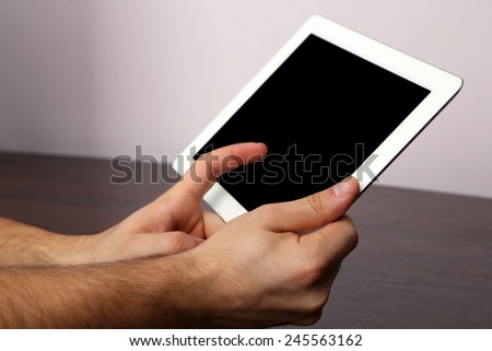 Hands using tablet PC on wooden table and light background
