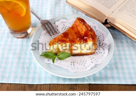 Cheese cake in plate, cup of herbal tea and books on tablecloth