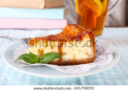 Cheese cake in plate, cup of tea and books on tablecloth