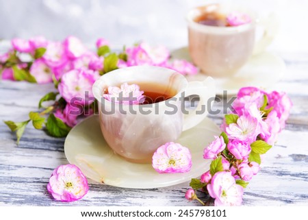 Beautiful fruit blossom with cup of tea on table on grey background