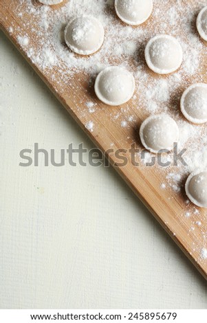 Raw dumplings on cutting board on table close-up