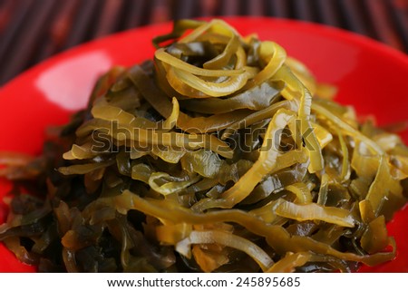 Seaweed in red bowl on bamboo mat background