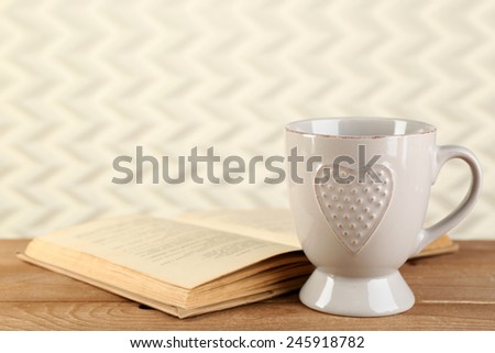 Cup of tea and book on table, on light background
