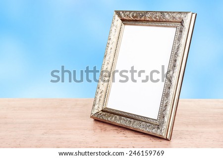 Photo frame on wooden table on blue background