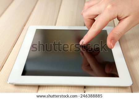 Hand using tablet PC on wooden table background