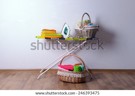 Ironing board with laundry on light background