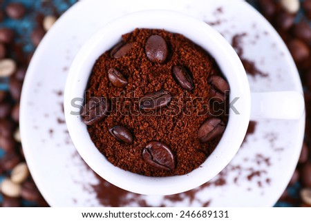 Coffee beans in white ceramic cup with saucer closeup