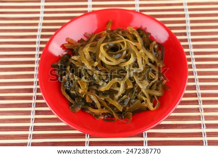 Seaweed in red bowl on bamboo mat background