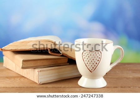 Cup of tea and books on table, on bright background