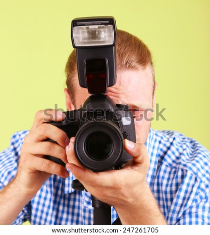 Handsome photographer with camera on monopod, on green background