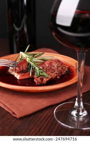 Glass of wine with grilled steak in wine sauce on dark background